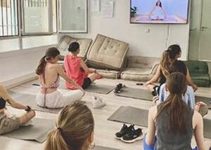 Grupo de personas practicando yoga y viendo la televisión.